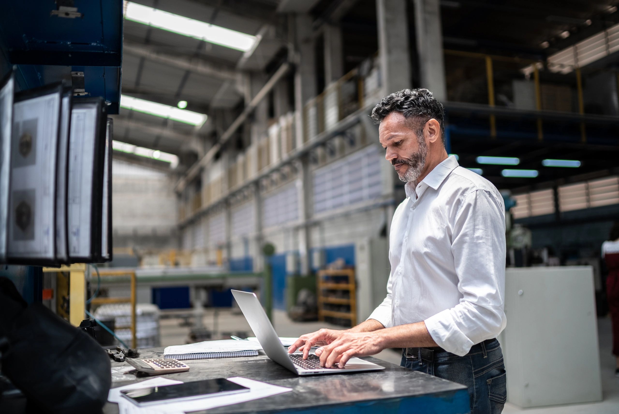 Facilities manager using a laptop on a manufacturing floor